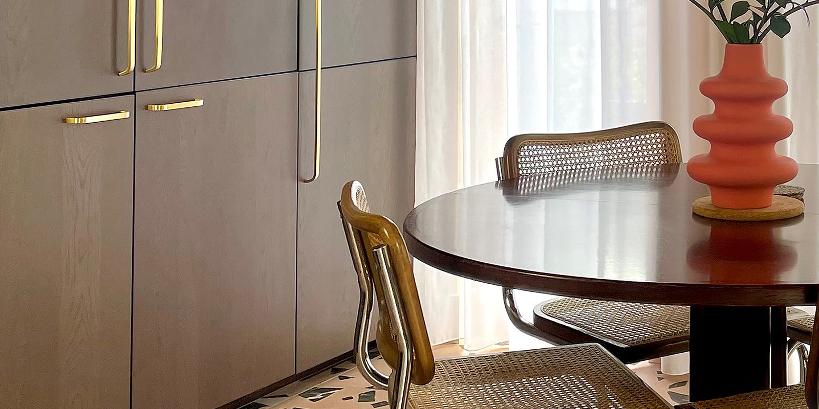 room with a dining table and cupboards with gold handles